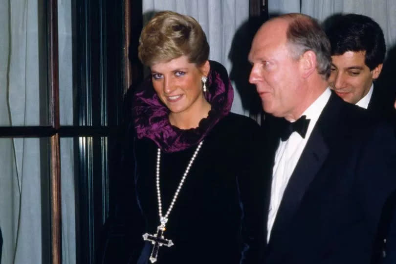 Princess Diana arriving at a charity gala wearing the 'Attallah Cross' crucifix pendant designed by Garrard along with a purple velvet evening gown